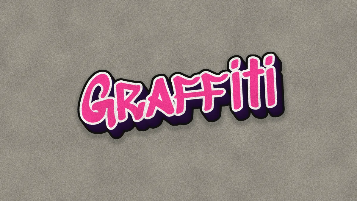 The word "Graffiti" in pink spray-paint letters with a white outline and a dark purple 3D drop on a gray wall